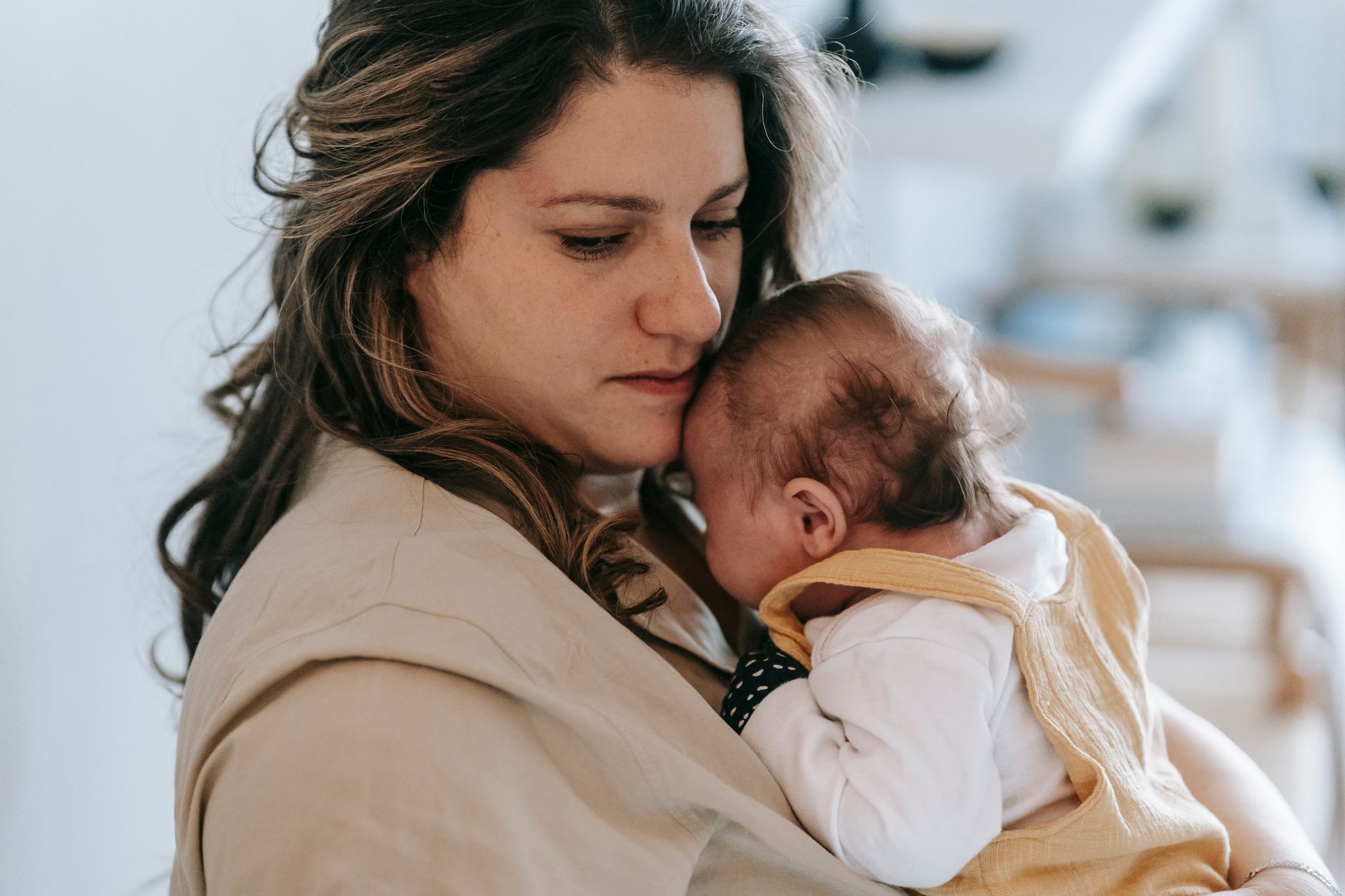 A caregiver gently holding a swaddled infant indoors