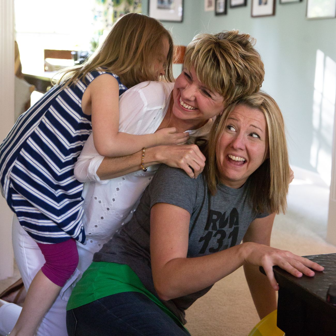 A mother laughing warmly while hugging her young daughter